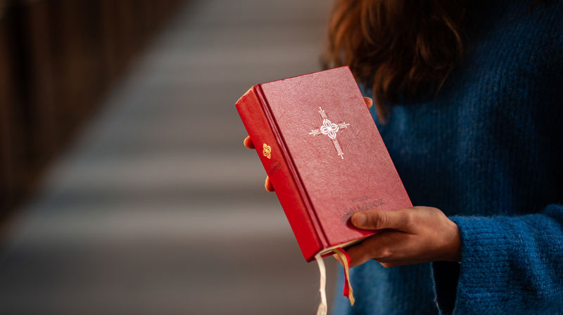Kirkevert deler ut salmebok før gudstjeneste. Foto: Kirkerådet