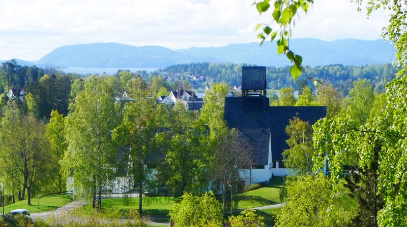 Holmen kirke i frodig sommerlandskap. Fotograf: Norunn Edvardsen