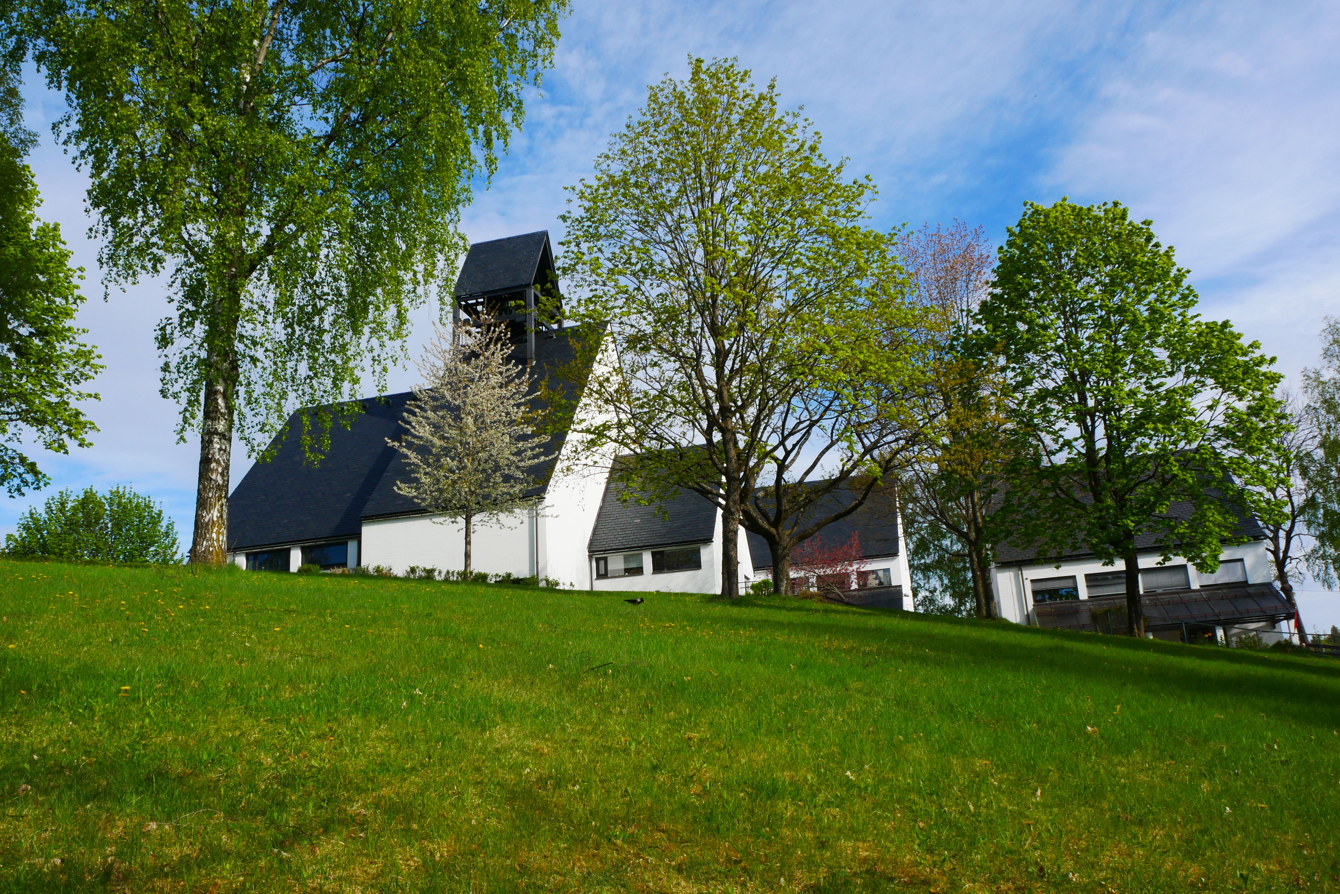 Holmen kirke i frodig grønt landskap. Fotograf: Norunn Edvardsen