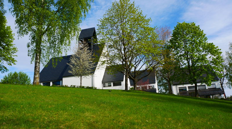Holmen kirke i frodig grønt landskap. Fotograf: Norunn Edvardsen