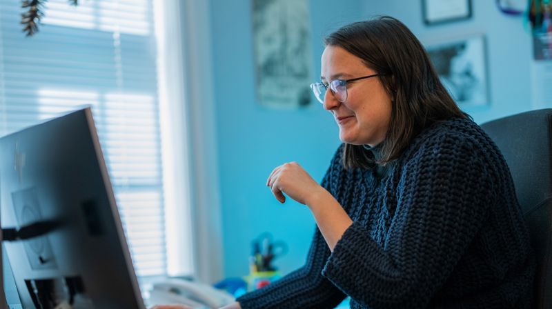 En kvinne sitter foran pc-skjerm på kontor