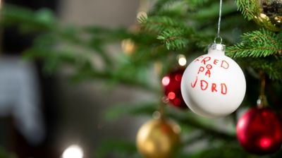 Ei julekule henger på juletreet. På kula er det skrevet med rød tusj: Fred på jord.