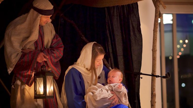 Levende julekrybbe. Maria og Josef. Maria holder Jesus i armene. Josef holder en lykt.