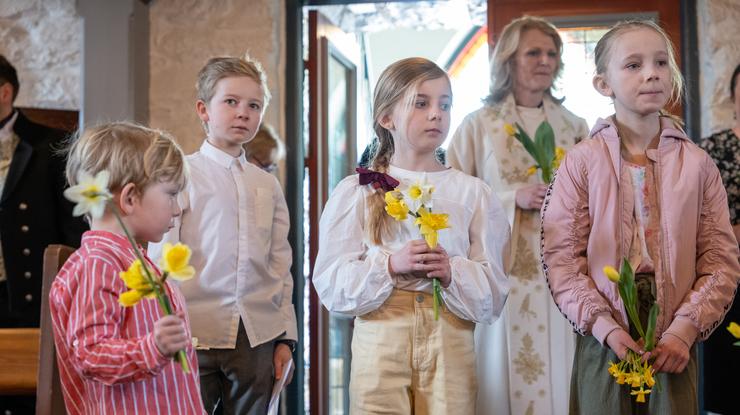 Barn som holder påskeliljer inn i kirken