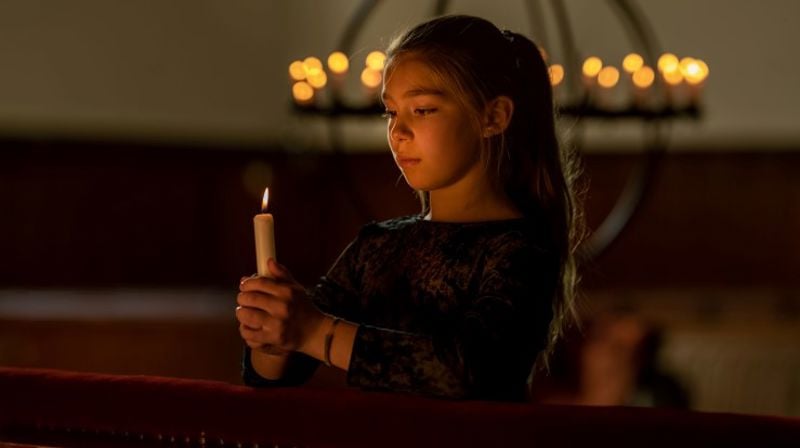 Jente tenner lys foran alterringen. Det er allehelgen i kirken.