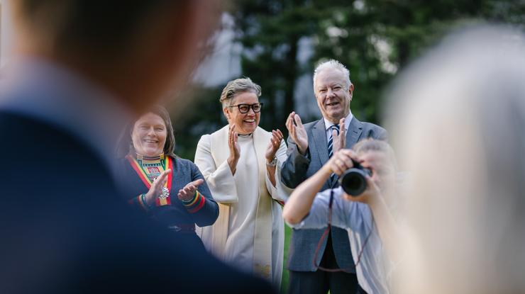 Et par blir fotografert. Sammen med fotografen står prest og forlovere og klapper entusiastisk i hendene.