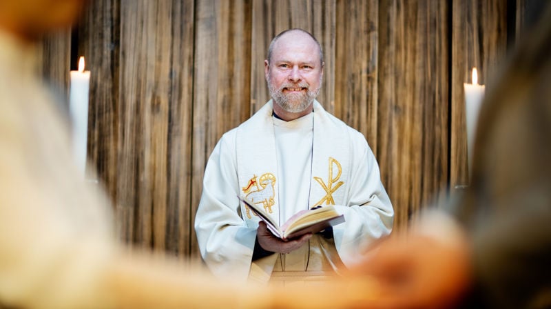 En prest som vier et brudepar. Vi kan skimte hendene til brudeparet som avlegger løfter til hverandre.