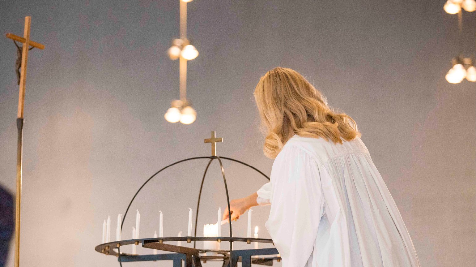 En konfirmant tenner et lys i lysgloben.