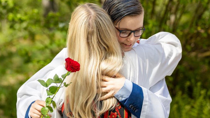 Det er konfirmasjon i kirken. Tre jenter i bunad i kirkerommet som er glade