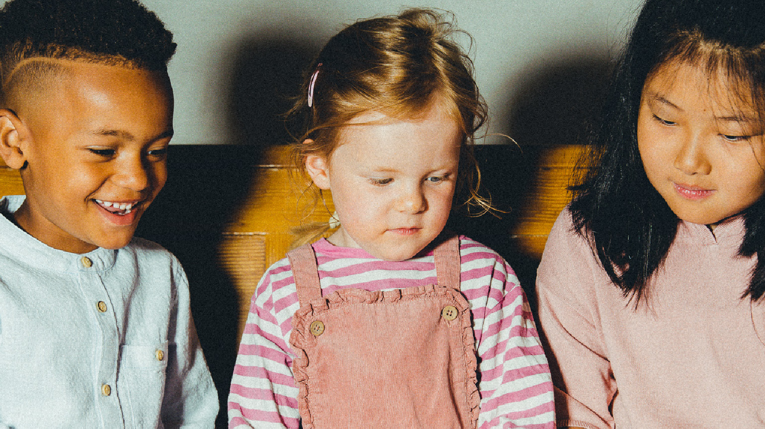 Tre barn sitter tett og konsentrert