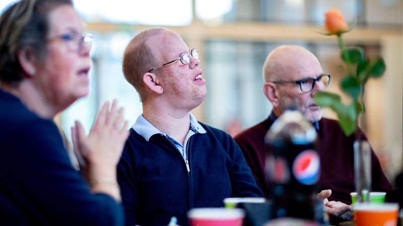 Nært portrett av flere personer som sitter på kirkekaffe