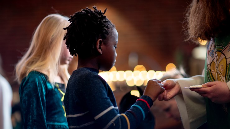 Et barn som mottar nattverd fra presten