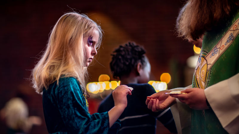 Et barn som mottar nattverd fra presten