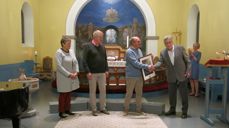 Oscar J. Garnes deler ut diakoniprisen i Kviteseid kyrkje til Astrid og Jan Gunnar Breivik (t.v.) og Håkon Birkeland.