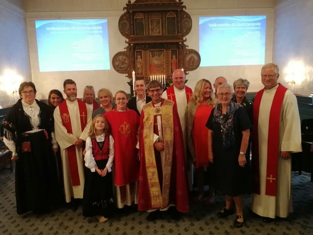 Kristine Borgen i rød messehakel i midten sammen med biskop Stein Reinertsen, familie, vanner og kirkelige tilsatte.