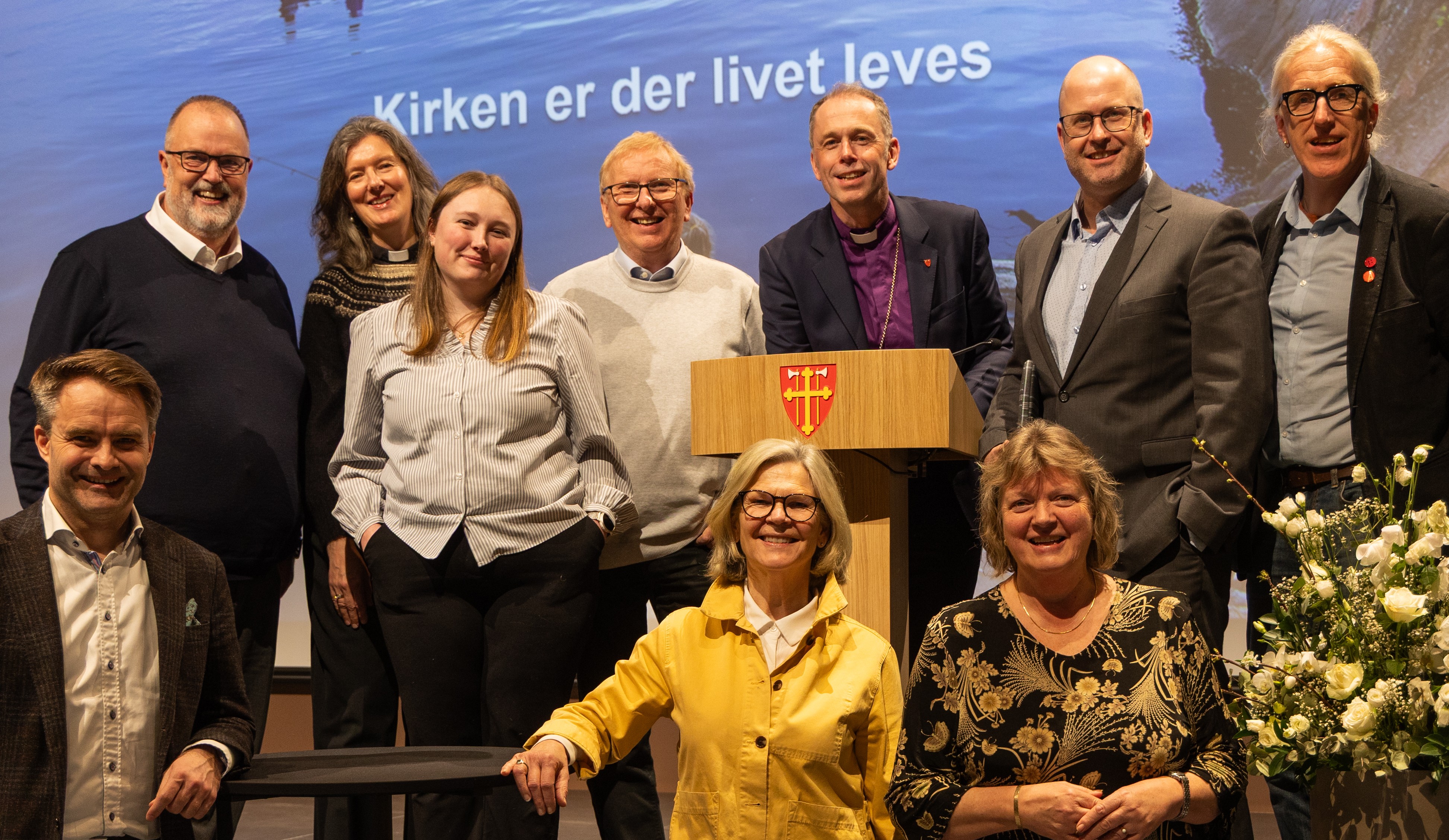 Hamar bispedømmeråd under Kirkemøtet 2026. Bak fv: Ole Jacob Dyrnes, Therese Wagle Bazard, Vanja Hole Joramo, Gunnstein Endal, Biskop Ole Kristian Bonden, Trond Enemo (vara for Adrian Sagvold Grøndahl), Sveinung Moesgaard Skjesol. Foran f.v: Stiftsdirektør Freddy Knutsen, Anne Kristine Rossebø, Bispedømmerådets leder Kjersti Drtina Øversveen. Forfall: Vidar Haugen. Foto: Heidi Olsen / Den norske kirke