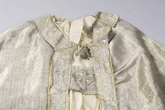 Kåpen fra 1864 har sølvkniplinger langs kantene, og et sølvkors på spennet.