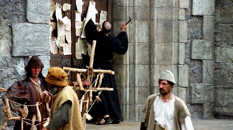 I 1517 slo Marin Luther opp sine 95 teser mot avlatshandelen på døren til slottskirken i Wittenberg i Tyskland. Bildet er fra filmen «Luther». Foto: UPI