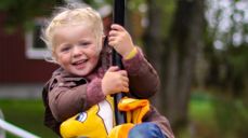 Blid jente i farta på huske.