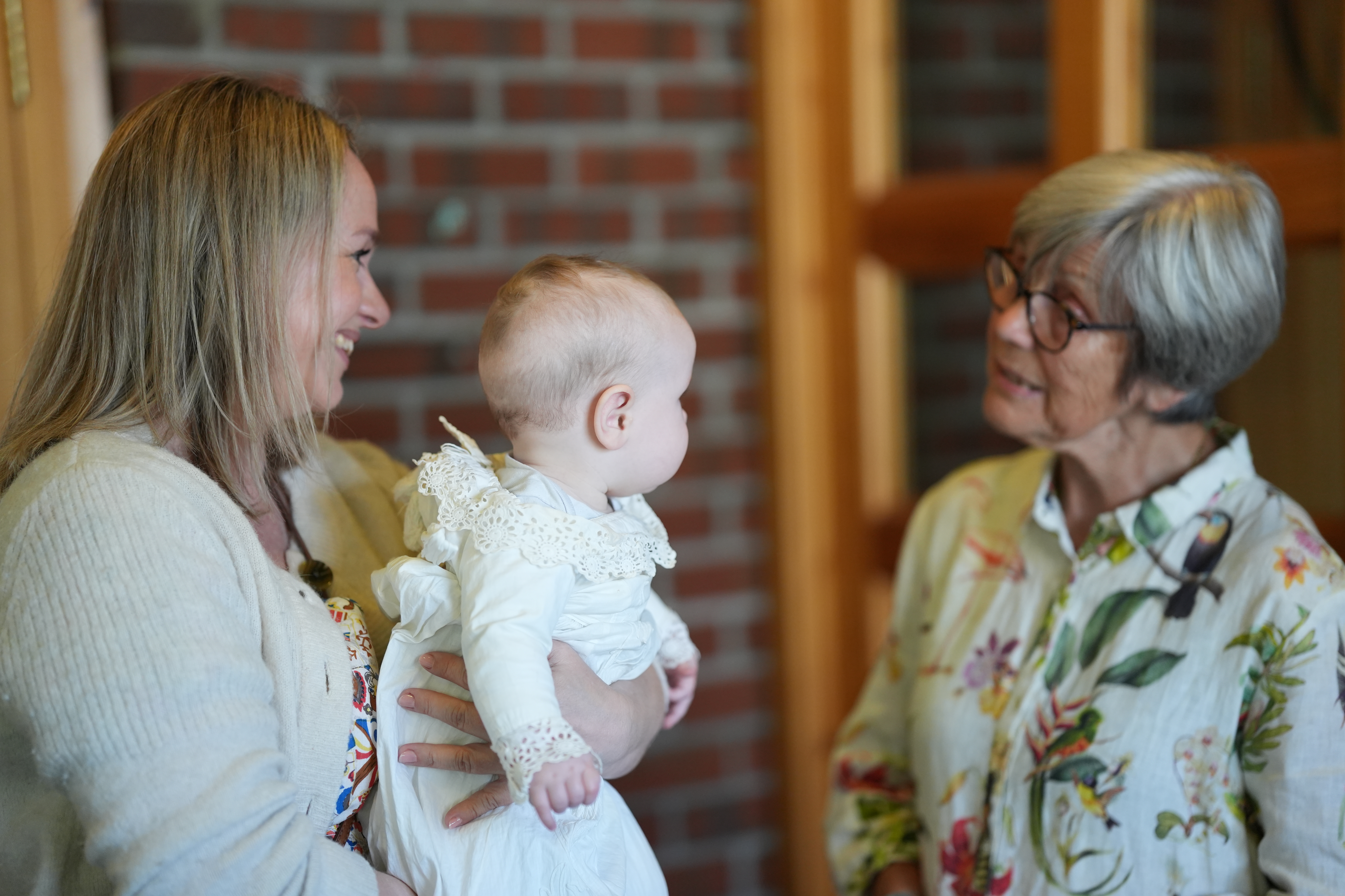 Fadder til dåpsbarnet snakker med dame. Foto.