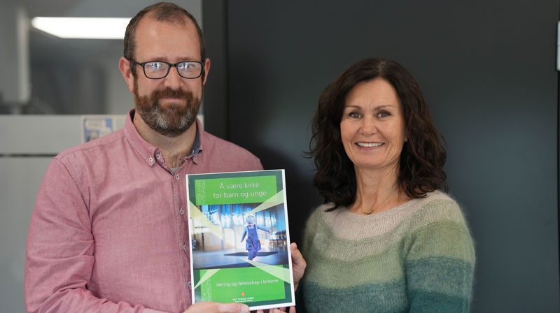Sven-Ove Rostrup overleverer rapporten Å være kirke for barn og unge til kirkeverge Mette Svanes.