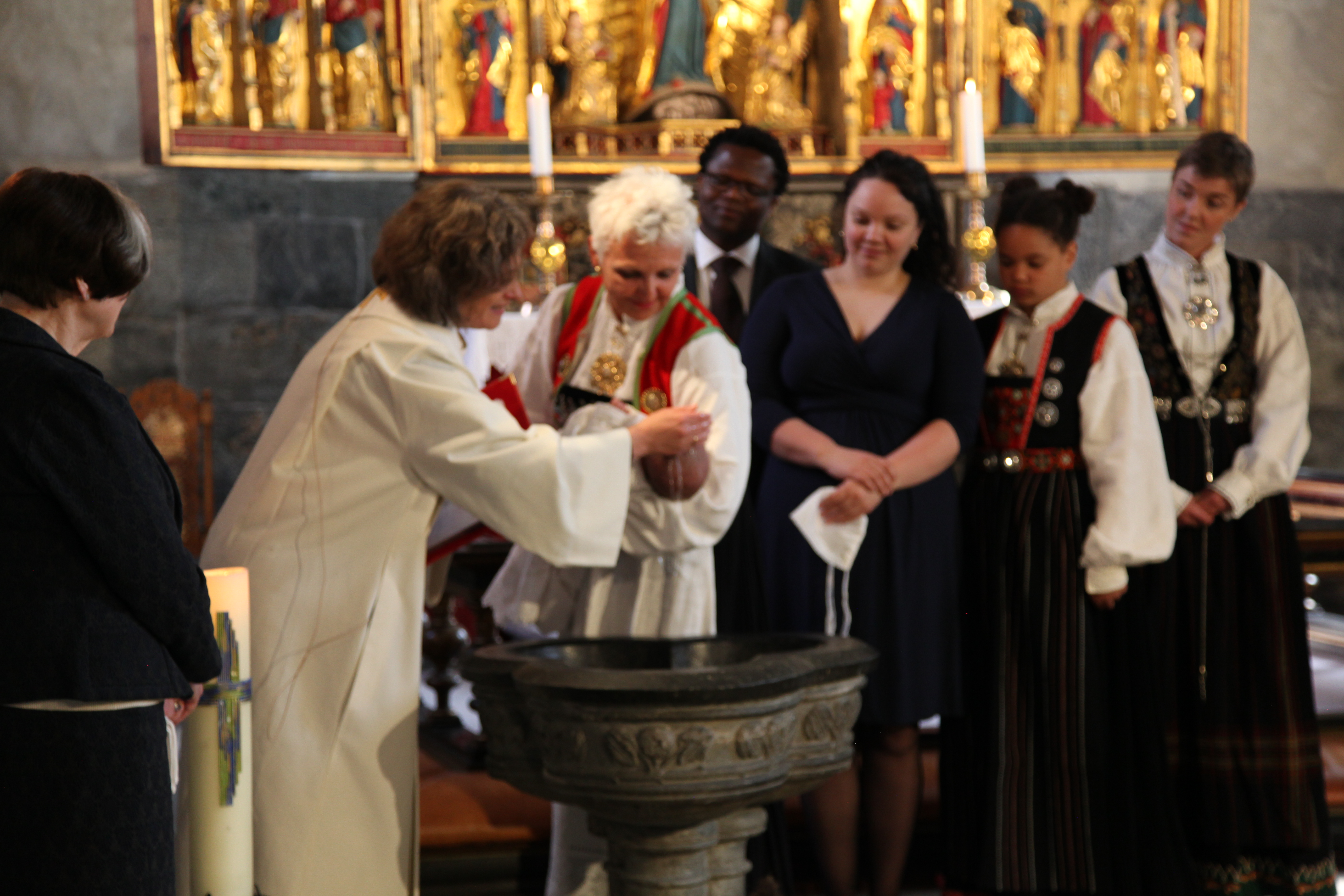 Dåpsfølge og prest ved døpefonten i Marakirken.