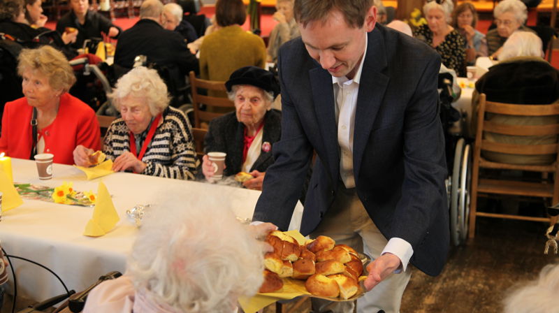 Domkantor Sigurd Melvær Øgaard serverer påskeboller under påskekonserten for eldre i Bergen domkirke.