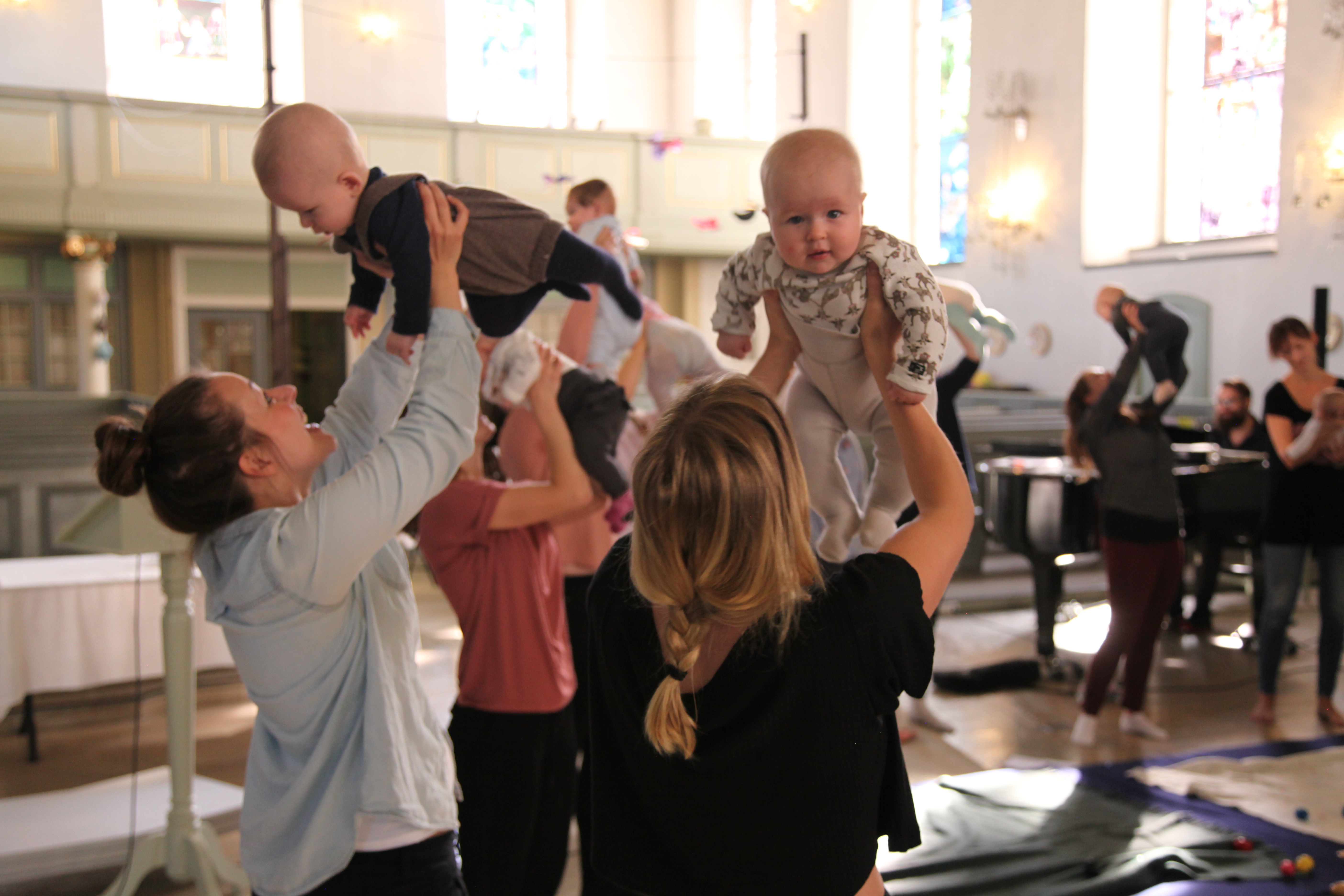 Babyer holdes opp av foreldre på babysang i Nykirken.