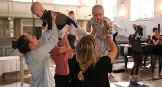 Babyer holdes opp av foreldre på babysang i Nykirken.