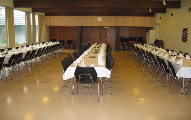Foto av storsalen med tre langbord som er dekket for fint besøk.