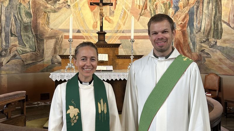 Kantor Asbjørn Snilstveit og sokneprest Anne Line Holme Kroken, begge i embetsdrakt, framføre altartavla i St Markus kyrkje