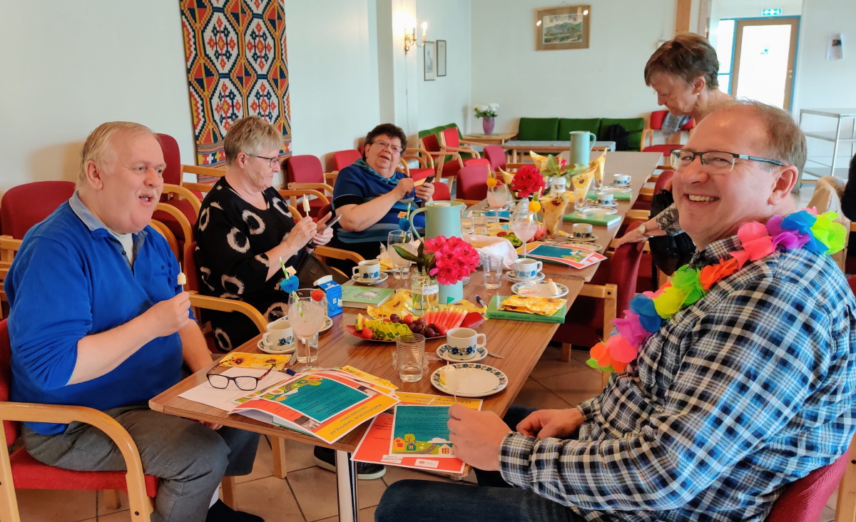 Diverse muntre personer samlet rundt et bord på onsdagstreff i St Markus menighetssal