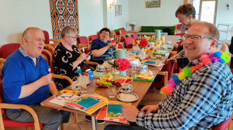 Diverse muntre personer samlet rundt et bord på onsdagstreff i St Markus menighetssal