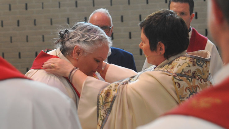 Biskopen legger en stola over skuldrene til den nye kapellanen i Søreide, Gunn Austad. Den er et tegn på at man har en vigslet tjeneste i kirken. Foto: Jens Z. Meyer