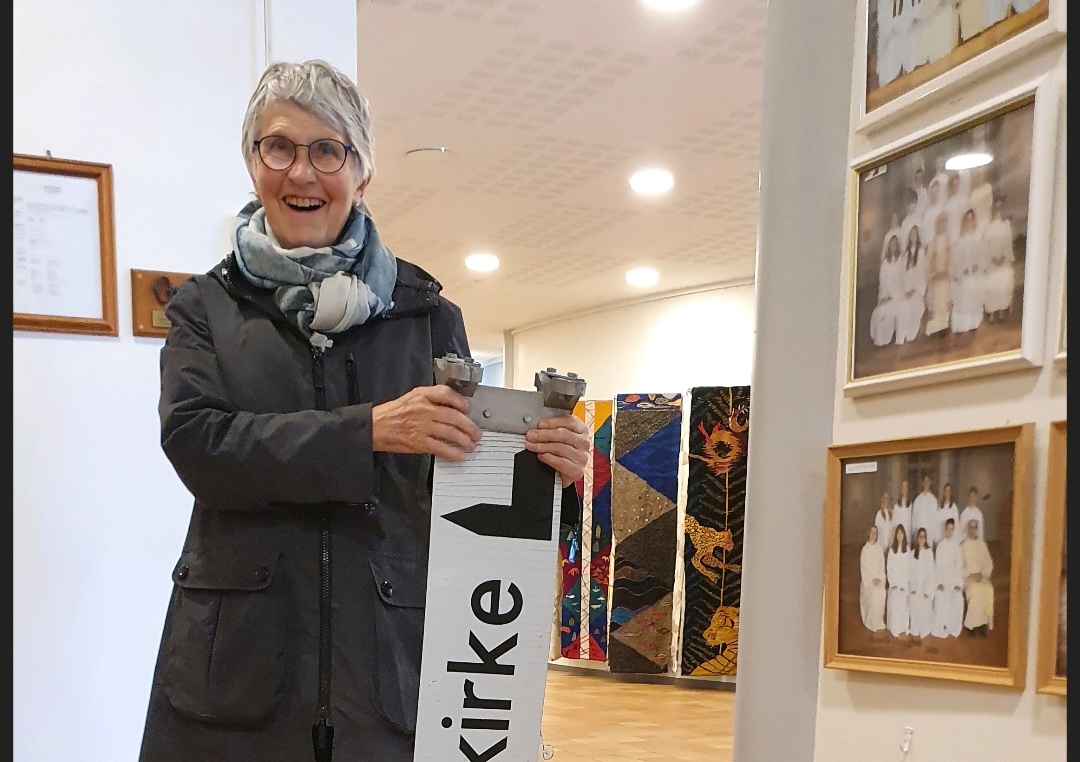 Foto: Monica Nilsen. Her kommer Anna Helene innom kirka med skiltet som viser vei til kirka. Den lå nede på bakken i Kirkeveien.