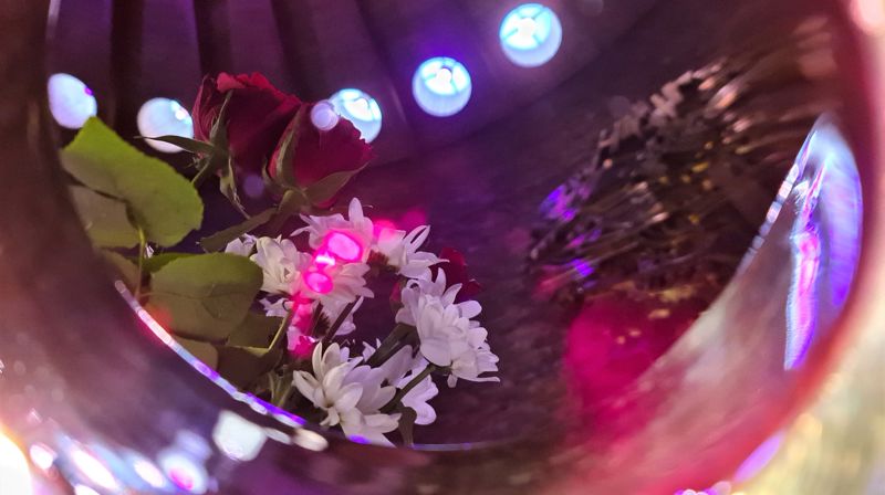 Alterblomster og altersmykke speiles i nattverd-kalken med vin i Åssiden kirke.
