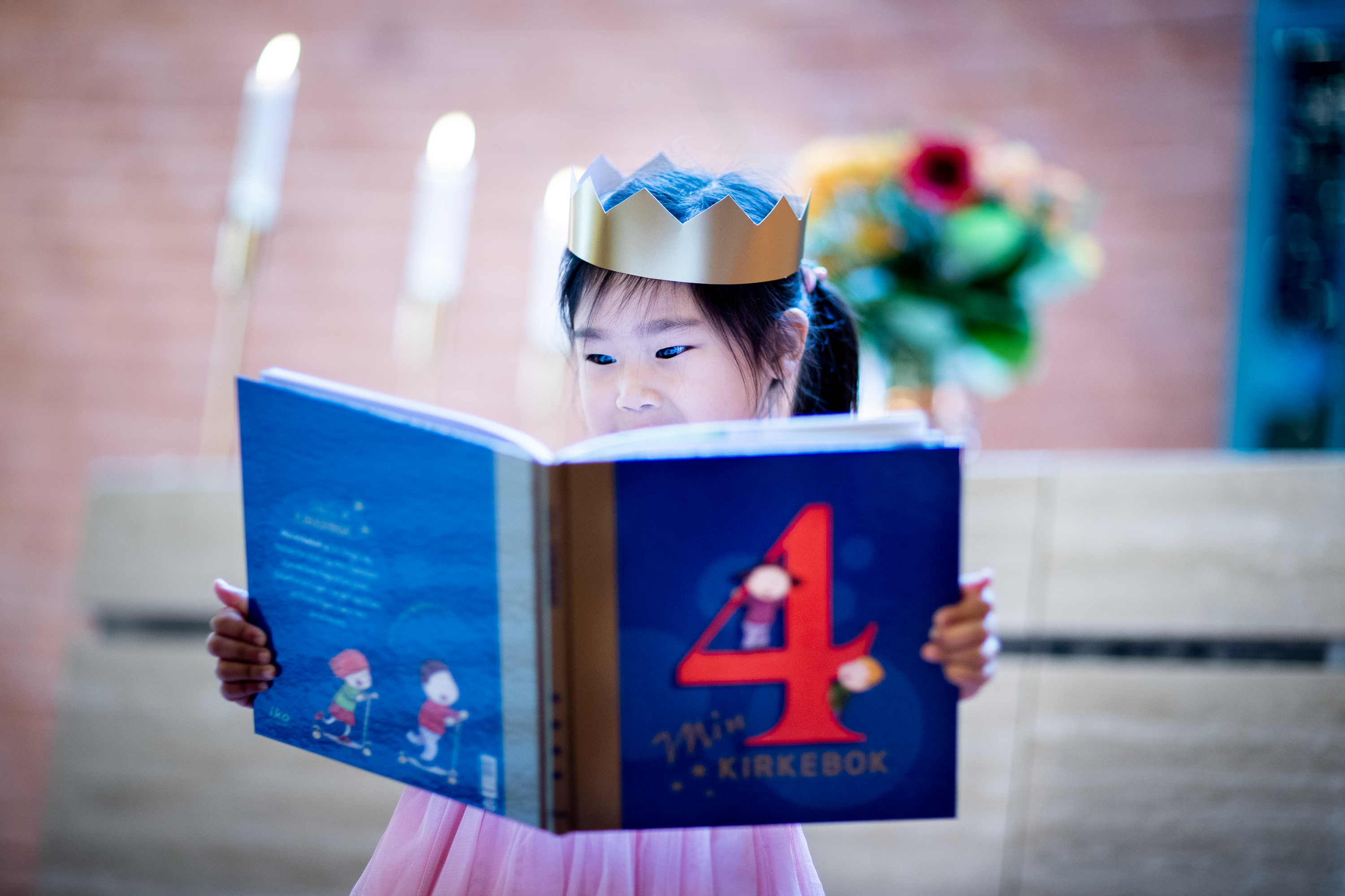 Fireåring med bok og krone i et kirkerom.