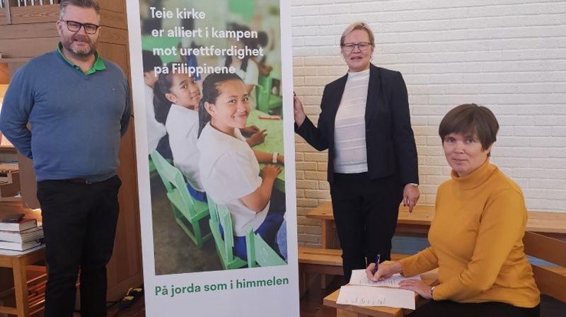 Marit Handeland, leder i Teie Menighetsråd signerer ny avtale. Hun er «omgitt» av Sverre Vik og leder i Misjonsutvalget, Gunn Marit Langedrag. (Foto: Britt Flaatten)