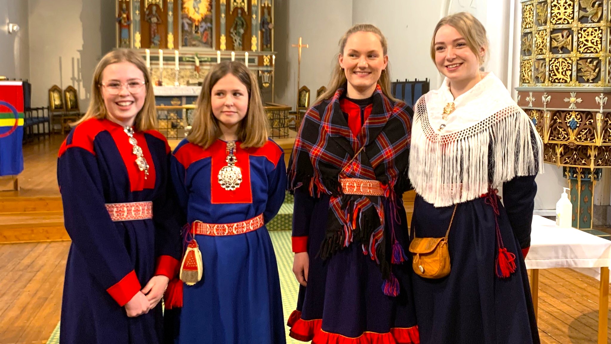 Fire unge kvinner i samekofte foran domkirkens alter