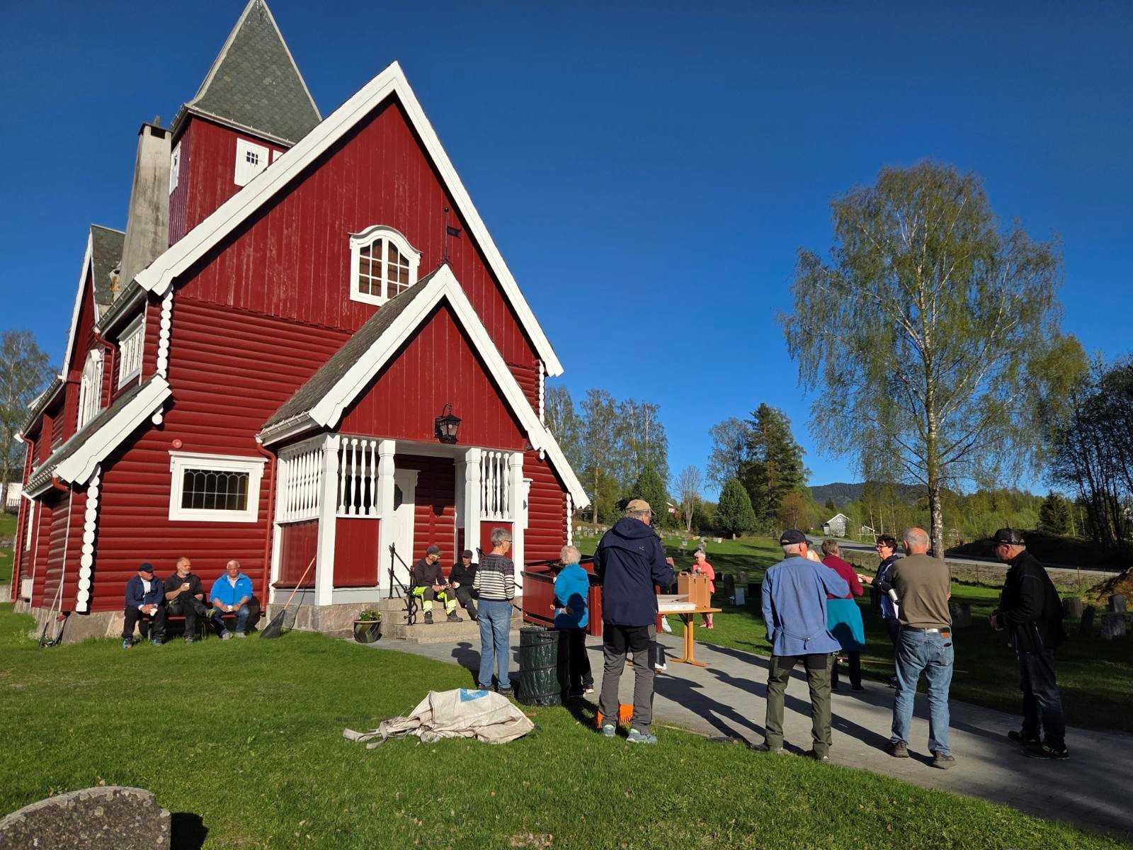 Dugnaden er ferdig og kaffe og kringle ble tatt i solveggen ved Moen kirke. Foto Kirken i Gran 2025.