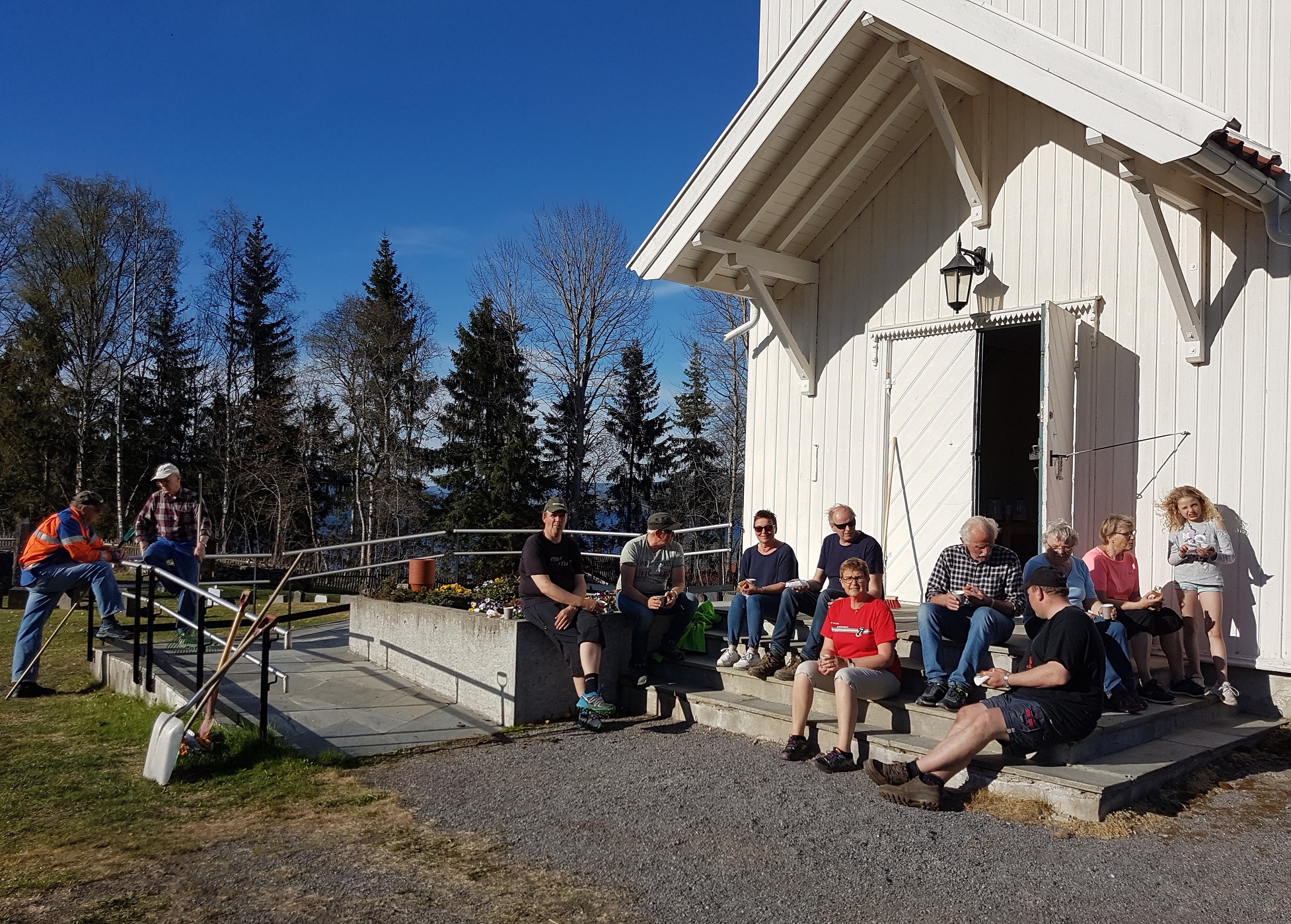 Dugnadsgjengen på Sørum kirkegård tok kaffen på kirketrappa i ettermiddagssola i mai i fjor (foto Bjoneroa menighetsråd).