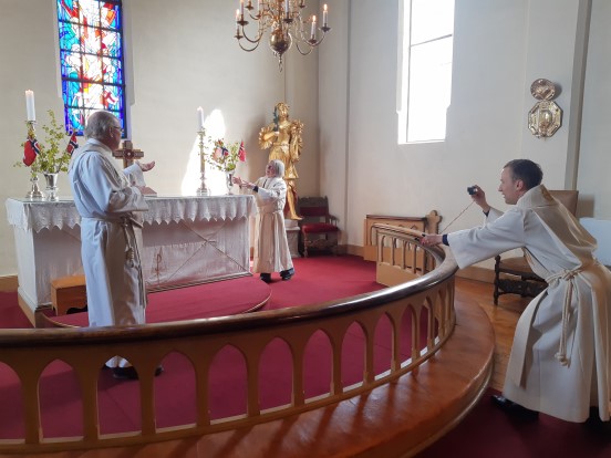 Sokneprestene i opptak til 17. mai-gudstjeneste i Tingelstad kirke. Fra venstre Dagfinn Magnus, Karin H. Bøe og Daniel Håkegård med kamera. (Foto: Kirken i Gran). 