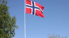 Det norske flagget vaier i vinden omkranset av bjørk og morell i vårblomstring. Foto: Kirken i Gran, Inger S. Haug.