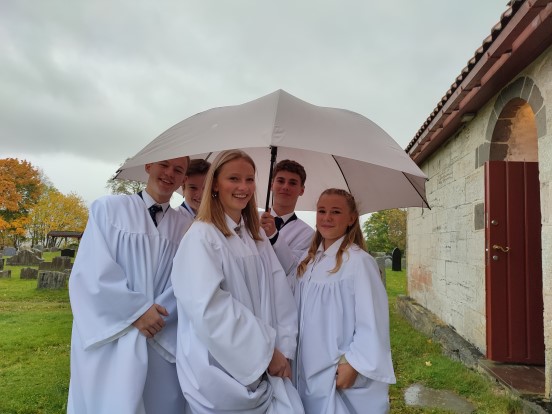 Her er noen av konfirmantene i Nikolaikirken 3. oktober. Med hjelp av en stor paraply holdt de seg tørre i regnværet før de gikk i prosesjon inn i kirka. (Foto: Daniel Håkegård).