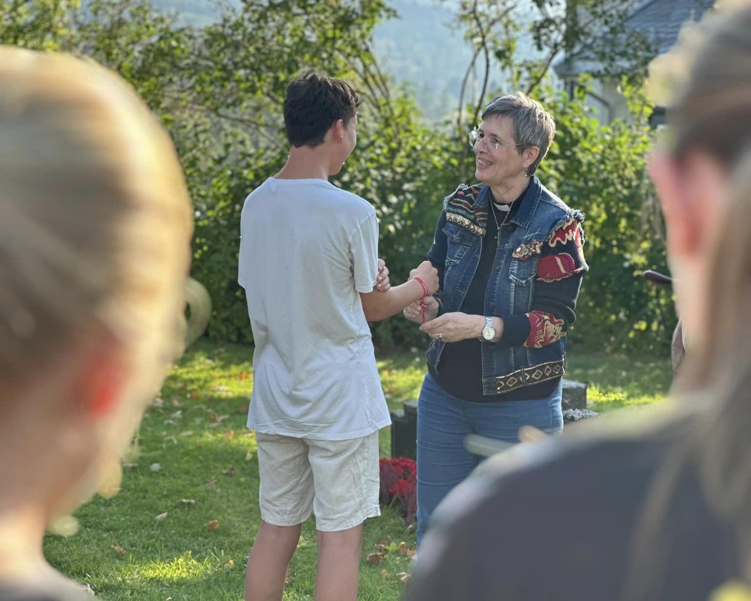 Under pilegrimsvandringen tidlig høst i 2024 fikk alle konfirmantene vennskapsbånd. Her knytter prest Anne Jørstad et av båndene på en konfirmant (foto Jane Dahl Sogn).