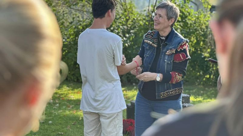 Under pilegrimsvandringen tidlig høst i 2024 fikk alle konfirmantene vennskapsbånd. Her knytter prest Anne Jørstad et av båndene på en konfirmant (foto Jane Dahl Sogn).