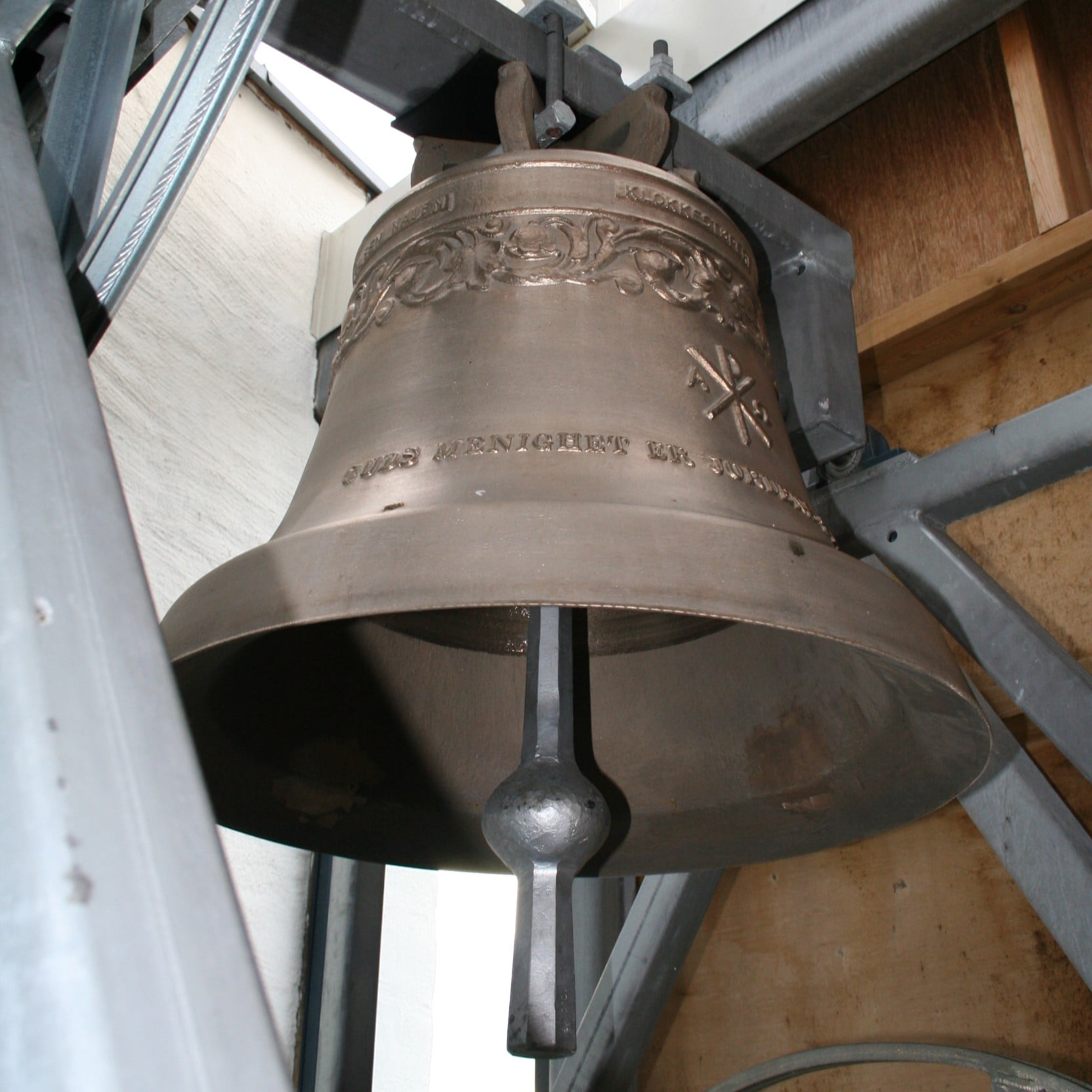 Den ene av de to kirkeklokkene som henger i klokketårnet ved Grymyr kirke. Foto: Kirken i Gran. 