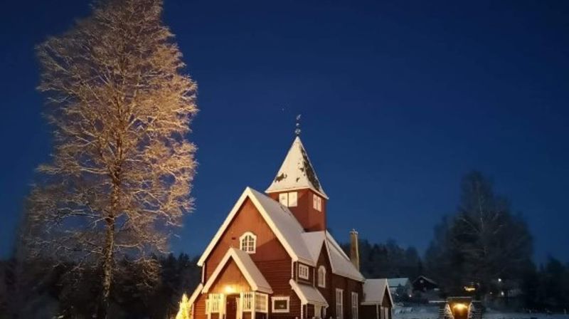 Moen kirke i nysnø og med juletreet tent, desember 2021. (Foto: Ruth Kari Sørumshagen). 