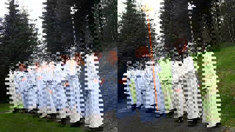 Menighetspedagog Ingunn Bergsager Våge leder prosesjonen inn til konfirmasjon i Rossabø kirke.