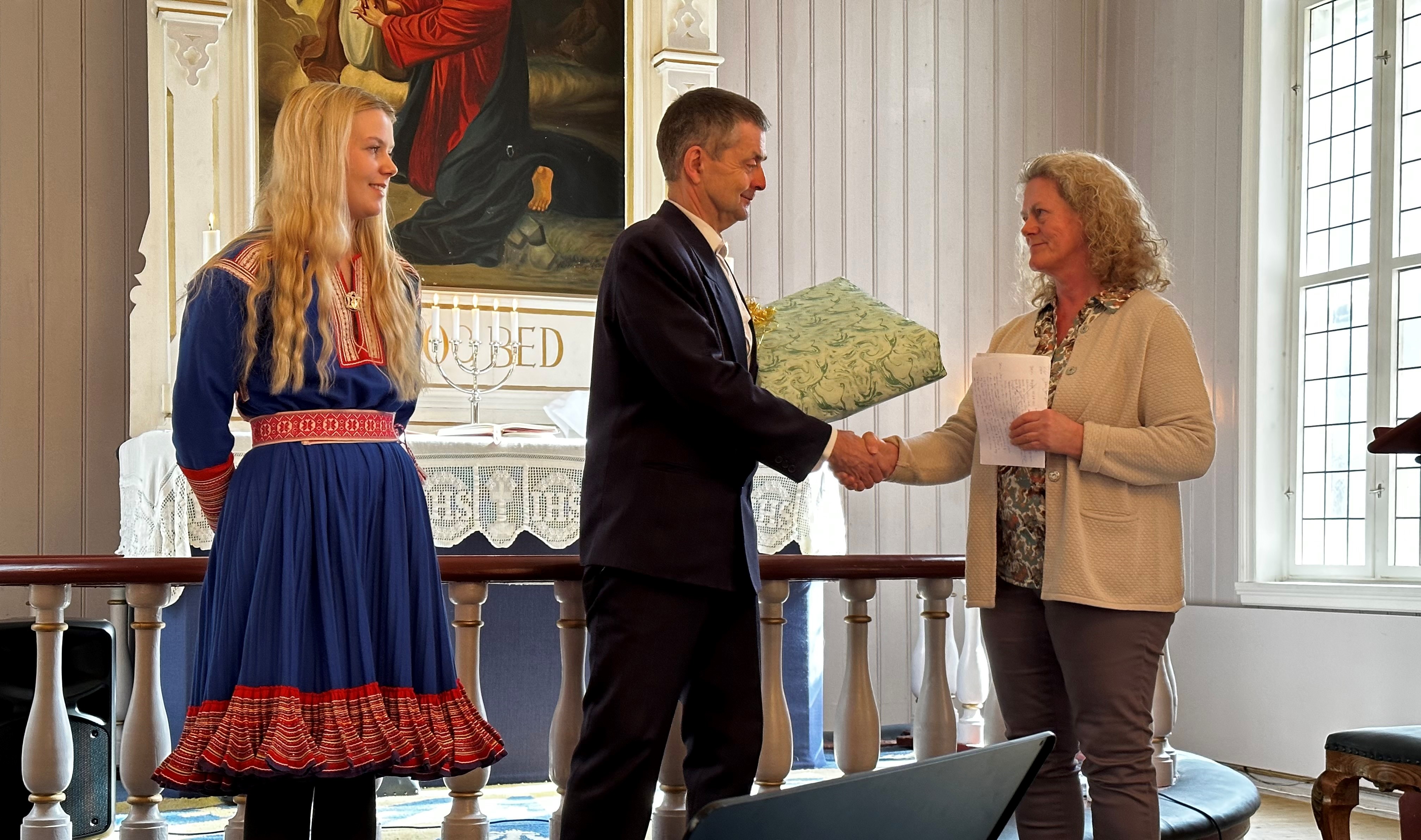 Jens Rikheim får gåve av soknerådsleiar Anne Karin Brugrand, Nora Henriette Grønvold Eriksen er òg tilstades på bilde. 